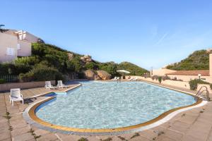 a large swimming pool with chairs and a mountain at Paradiso Pool Apartments by DomusAway in Costa Paradiso