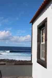 a white house with a window looking at the ocean at Dream By The Sea in Madalena