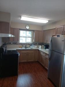 a kitchen with a stainless steel refrigerator and wooden cabinets at Green&White House in Coquitlam