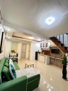 a living room with a green couch and a kitchen at Z House of Guest- Airport Davao in Davao City