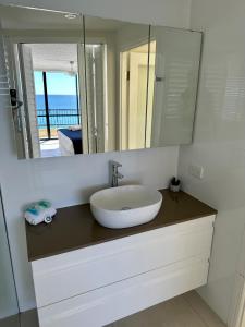 a bathroom with a sink and a mirror at Two Bedroom Ocean View Penthouse at Pelican Sands in Gold Coast