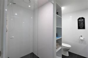 a white bathroom with a shower and a toilet at CBD apartment Cairns waterfront in Cairns