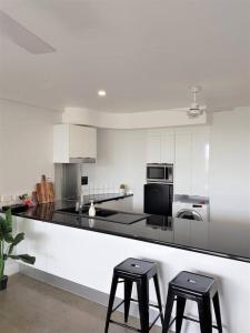 a white kitchen with two stools and a counter top at CBD apartment Cairns waterfront in Cairns