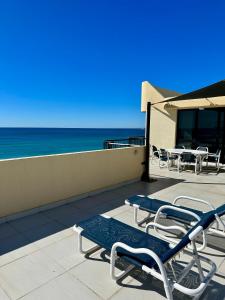 um pátio com cadeiras e mesas e o oceano em Two Bedroom Ocean View Penthouse at Pelican Sands em Gold Coast