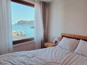 a bedroom with a bed and a large window at Seogwiporto in Seogwipo