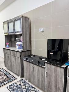uma cozinha com armários de madeira e uma televisão de ecrã plano em RAINA MUSLIM FRIENDLY HOMESTAY Perlis em Arau