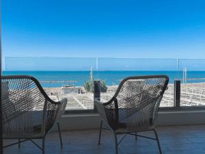 two chairs sitting in front of a window with the beach at 緩慢大鵬灣 in Donggang