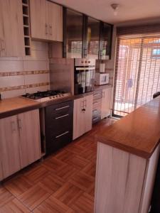 La casa di Gio في سانتياغو: مطبخ مع دواليب خشبية وارضية خشبية