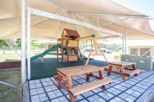 a playground with two benches and a swing at Crowdy Bay Eco Resort in Harrington