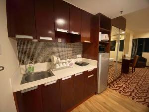 a kitchen with wooden cabinets and a sink and refrigerator at BV1 STUDIO KK CITY CENTRE WITH POOL NEAR Imago in Kota Kinabalu