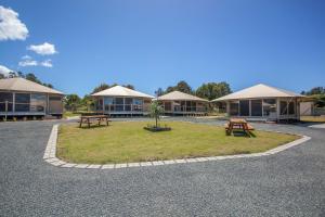 a building with two picnic tables in front of it at Crowdy Bay Eco Resort in Harrington