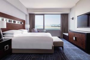 um quarto de hotel com uma cama grande e uma janela grande em Hong Kong SkyCity Marriott Hotel em Hong Kong