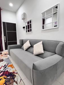 a gray couch in a living room with a window at RAINA MUSLIM FRIENDLY HOMESTAY Perlis in Arau