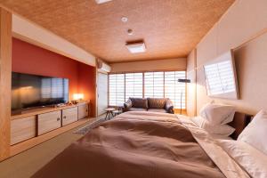 a bedroom with a large bed and a flat screen tv at Tsukasa Ryokan in Saga