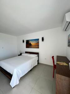 - une chambre blanche avec un lit et une chaise dans l'établissement Red Flamboyan Guesthouse and Restaurant, à Rincon