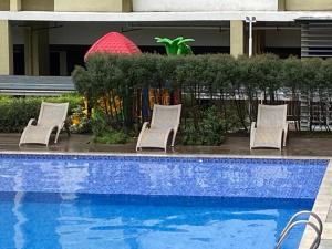 um grupo de cadeiras sentadas ao lado de uma piscina em Simple Studio @ MesaVerte Résidences em Cagayan de Oro