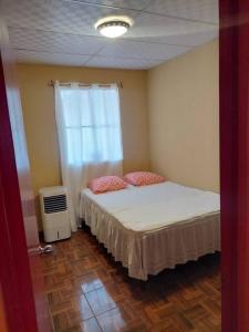 a small bedroom with a bed and a window at Yanira's house in Santa Ana