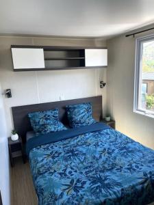 a bedroom with a blue bed and a window at Mobil-Home Baie Saint-Michel, Serre-Ponçon in Chorges