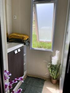 a bathroom with a window and purple flowers on the floor at Mobil-Home Baie Saint-Michel, Serre-Ponçon in Chorges