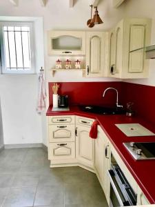 cocina con armarios blancos y encimera roja en Cottage de charme à la campagne, en Aulnoy