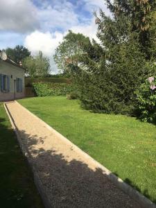 un patio de césped con una casa y un árbol en Cottage de charme à la campagne, en Aulnoy