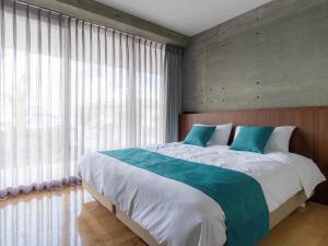1 dormitorio con 1 cama grande y ventanas grandes en Bosco Yomitan Resort Condminium, en Yomitan