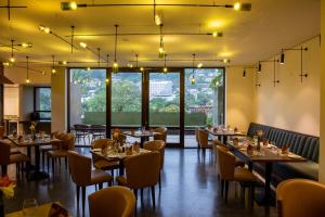 un comedor con mesas, sillas y ventanas en Lake Avenue Hotel Kandy, en Kandy