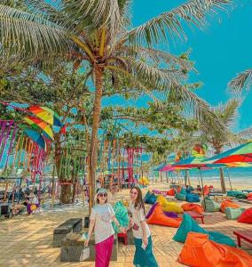 two women walking on a beach with palm trees at Hiên lương hotel &Apartment in Danang