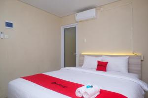 Un dormitorio con una cama con una toalla roja. en RedDoorz Plus near RS JIH Solo, en Solo