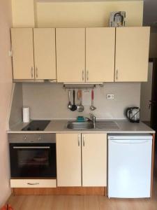 a kitchen with white cabinets and a sink and a stove at Ground Floor, Studio Apartment at Sunny Day 6 in Tŭnkovo