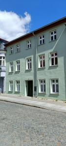 ein grünes Gebäude mit weißen Fenstern auf einer Straße in der Unterkunft Apartment 2 in Altstadt Angermünde in Angermünde