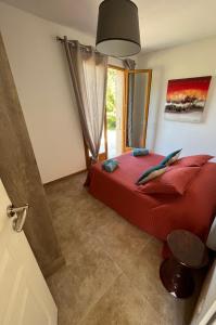 a bedroom with a red bed and a window at Villa CAlisti in Belgodère