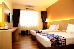 a hotel room with two beds and a desk at Hotel Seri Malaysia Seremban in Seremban