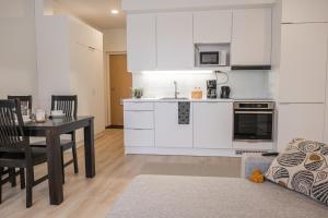 a kitchen with white cabinets and a table and a dining room at Snowflake Suites VIII with private sauna in Rovaniemi