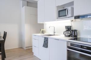 a white kitchen with a sink and a microwave at Snowflake Suites VIII with private sauna in Rovaniemi