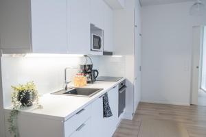 a white kitchen with a sink and a counter at Snowflake Suites VIII with private sauna in Rovaniemi