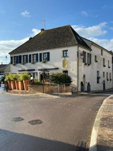 a white building with plants in front of a street at H&ocirc;tel - Restaurant Le Globe in Meursault