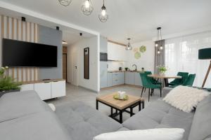 a living room with a couch and a tv and a table at Apartament Ernesto in Rewal