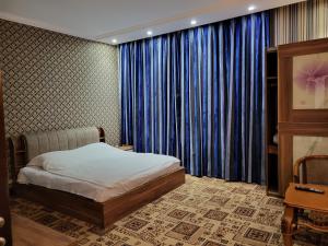 a bedroom with a bed and a window with blue curtains at seoul hotel in Shymkent