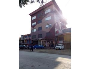 un edificio alto con coches estacionados al lado de una calle en Hotel lords Highway Inn, Gagal Khas, en Kangra