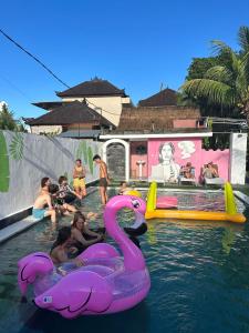 a group of people in a swimming pool with pink swans at Pillow Inn Ubud in Ubud