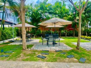 ein Tisch und Stühle mit Sonnenschirmen in einem Garten in der Unterkunft Hill Myna Holiday Park & Cafe in Strand Bang Tao + 5 Fotos