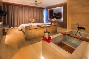 a hotel room with a bed and a bath tub at Hotel Komune and Beach Club Bali in Keramas