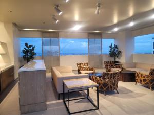 - un salon avec des chaises, des tables et des fenêtres dans l'établissement Cozy Zen Condo 2 beds, à Cebu