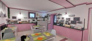 a restaurant with pink and purple walls and tables at Eden Guest House Colico in Colico
