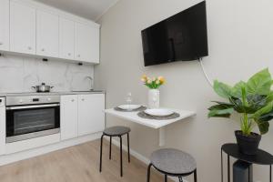 a kitchen with white cabinets and a small table with stools at Cute & Cozy Apartment Grochowska by Renters in Warsaw