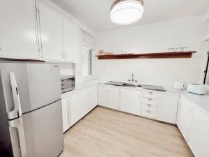 a white kitchen with a refrigerator and a sink at Gladstone Gem 3 - Suva CBD 2bd Apt in Suva