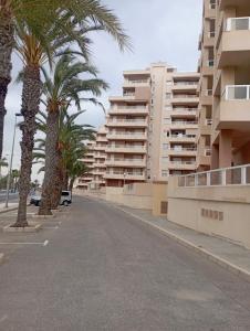 an empty street with palm trees and buildings at Beautiful Apartment in La Manga in San Javier