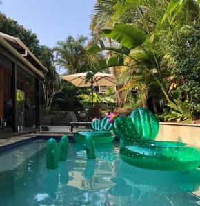 uma piscina com cadeiras insufláveis verdes num quintal em Beach Jungle - Hot Tub, Firepit & Pool in Beachside Oasis em Byron Bay