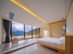 ein Schlafzimmer mit einem großen Bett und einem großen Fenster in der Unterkunft Drunken Valley Manor - Zhangjiajie National Forest Park in Zhangjiajie